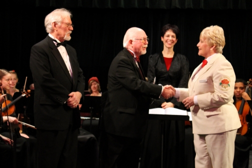 Board member emeritus Mike Shaw receives a donation check from President Korrie Hoeckendorf of the Royal Rosarian Foundation during the 2014 Winter Cheer concert.